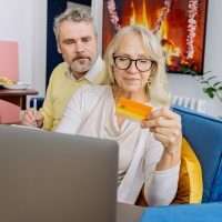 Image of a couple with a credit card entering the details into a laptop